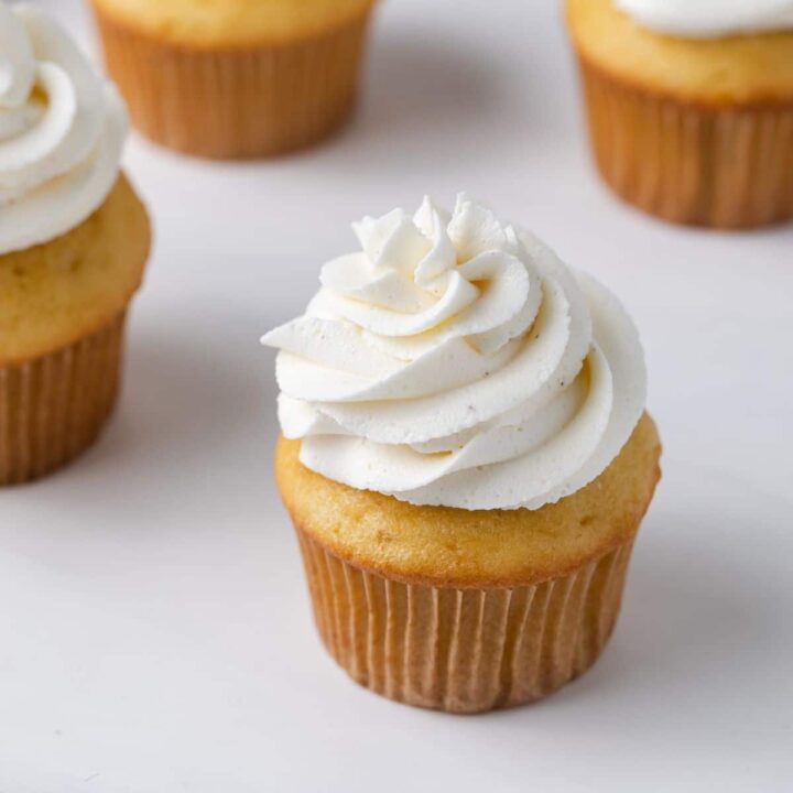 angled view of brown butter frosting swirled over yellow cupcakes