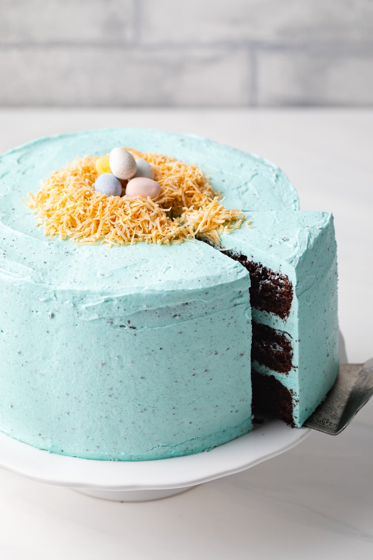 slice being taken out of chocolate easter cake with blue icing 