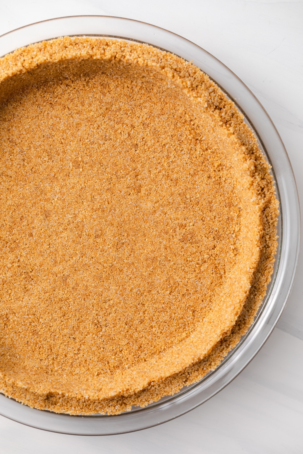 close up overhead of graham cracker crust in glass pie pan