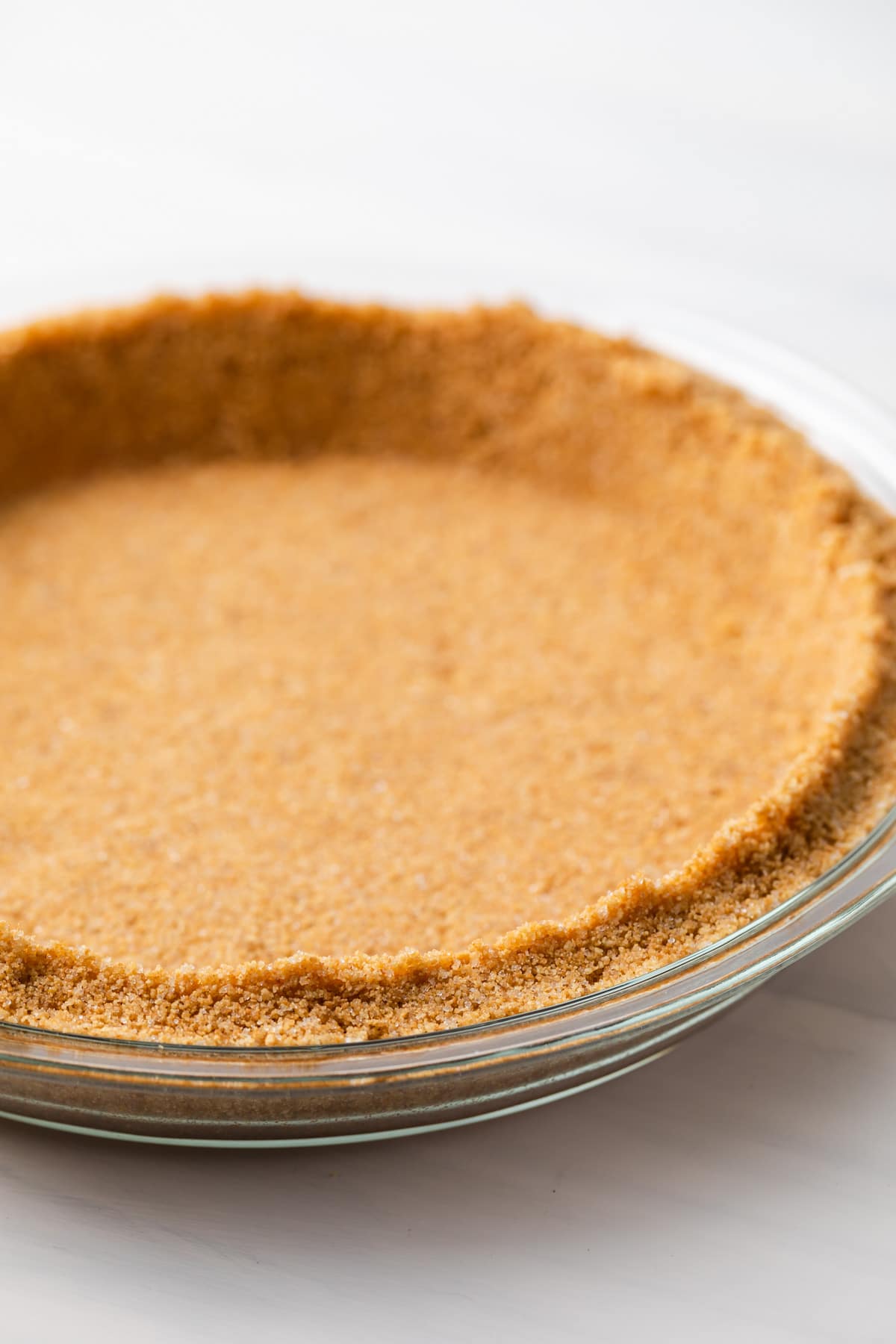 side view of graham cracker crumbs in glass pie plate