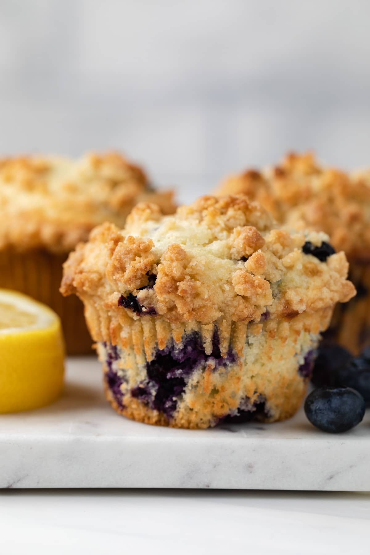 side view a muffin dotted with blueberries on a marble slab