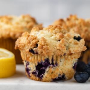 side view a muffin dotted with blueberries on a marble slab
