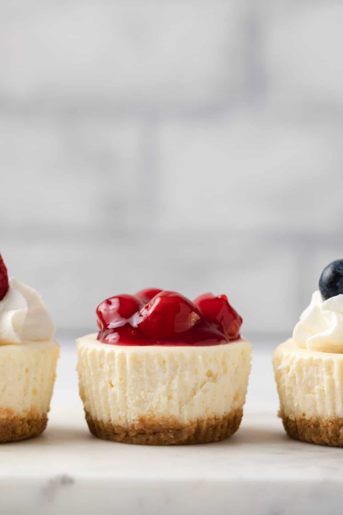 close up of mini cheesecake topped with cherry topping