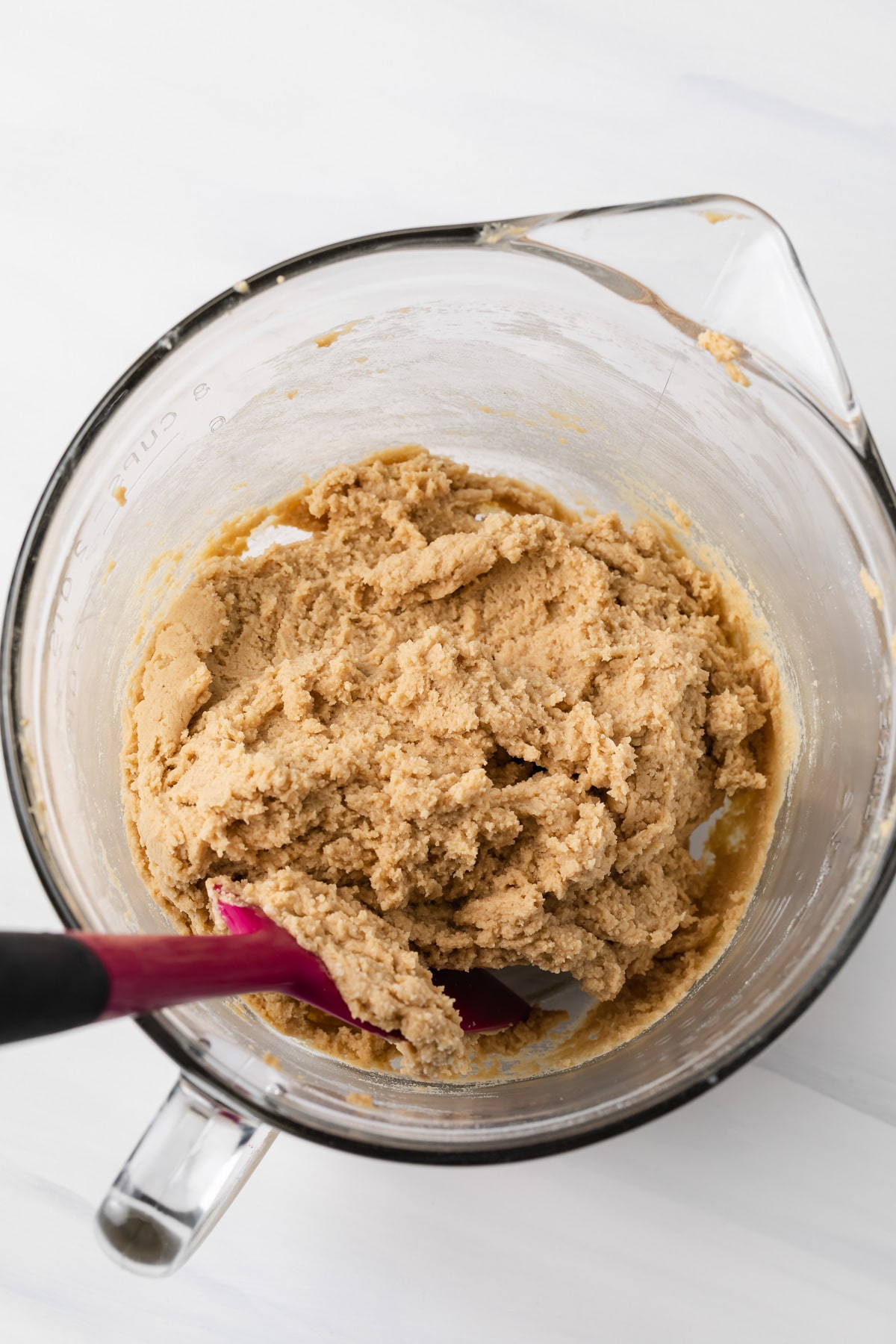 peanut butter cookie dough in glass bowl with pink spatula