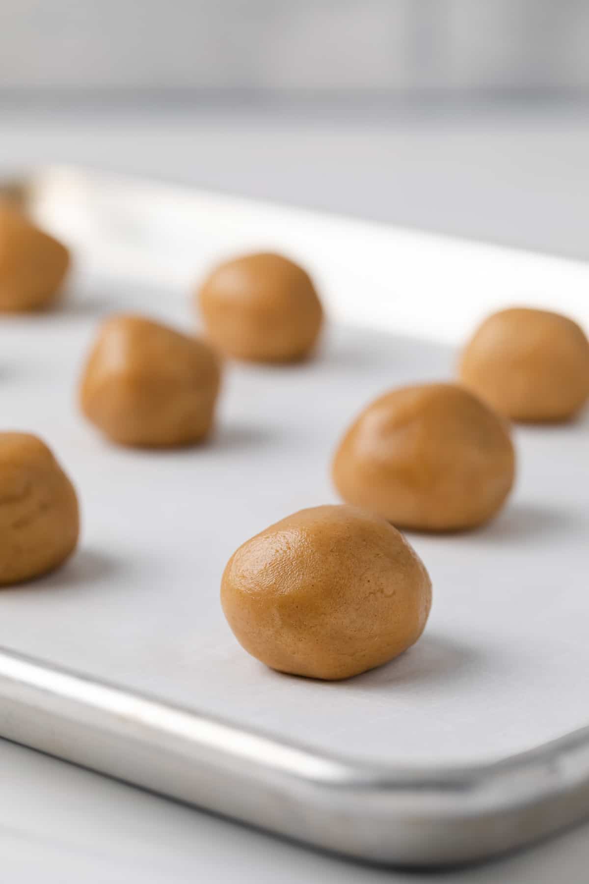 peanut butter cookie dough balls on baking sheet lined with white parchment paper