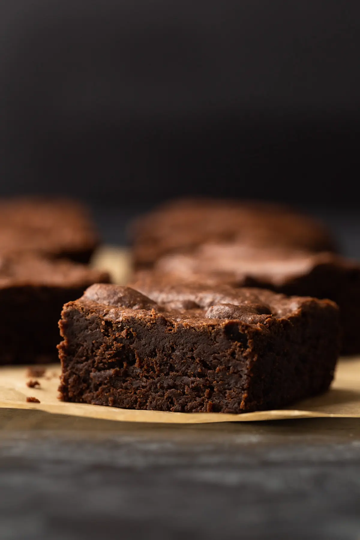 one chocolate brownie sitting on brown parchment paper