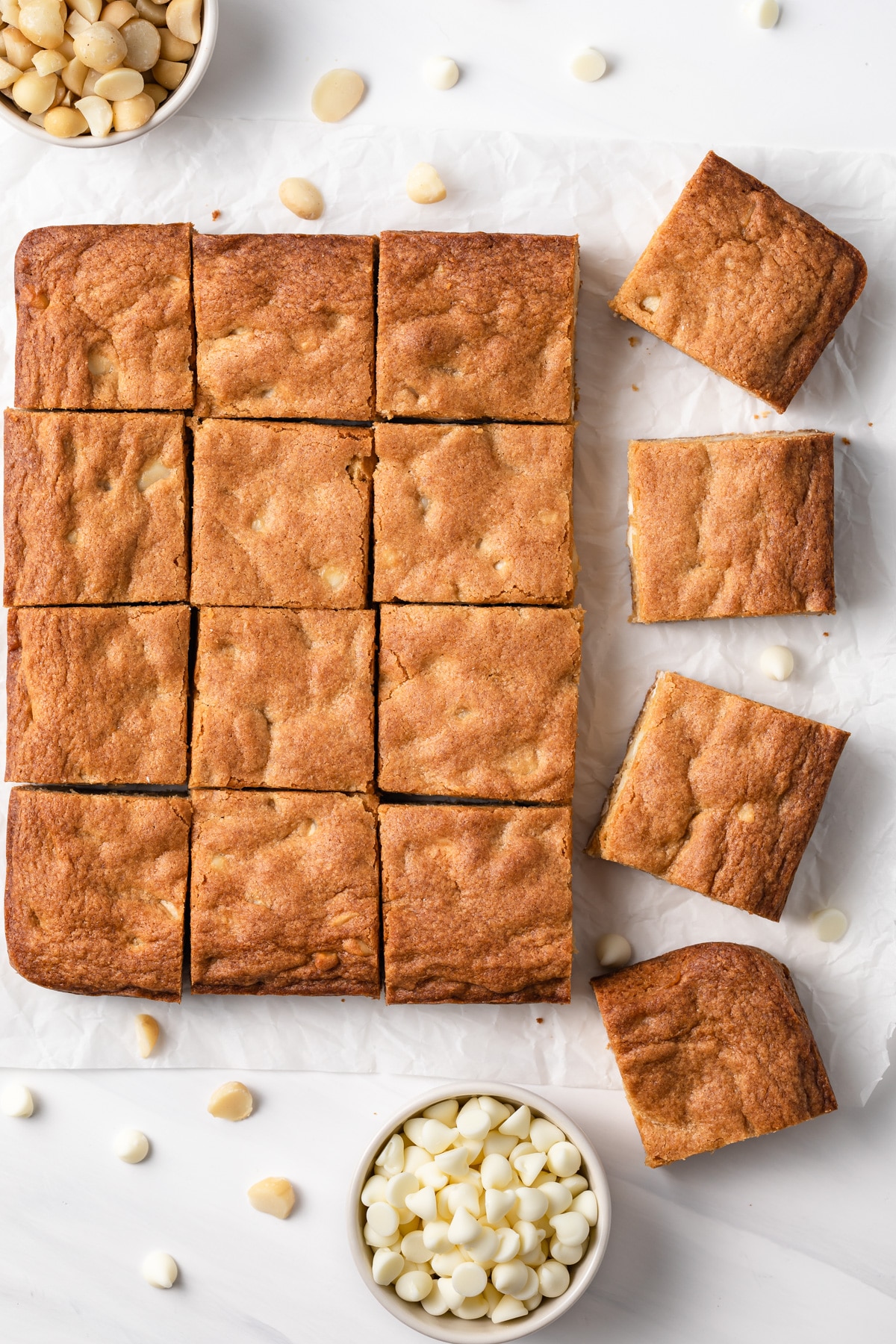 overhead of blondies with bowls of chocolate chips and macadamia nuts