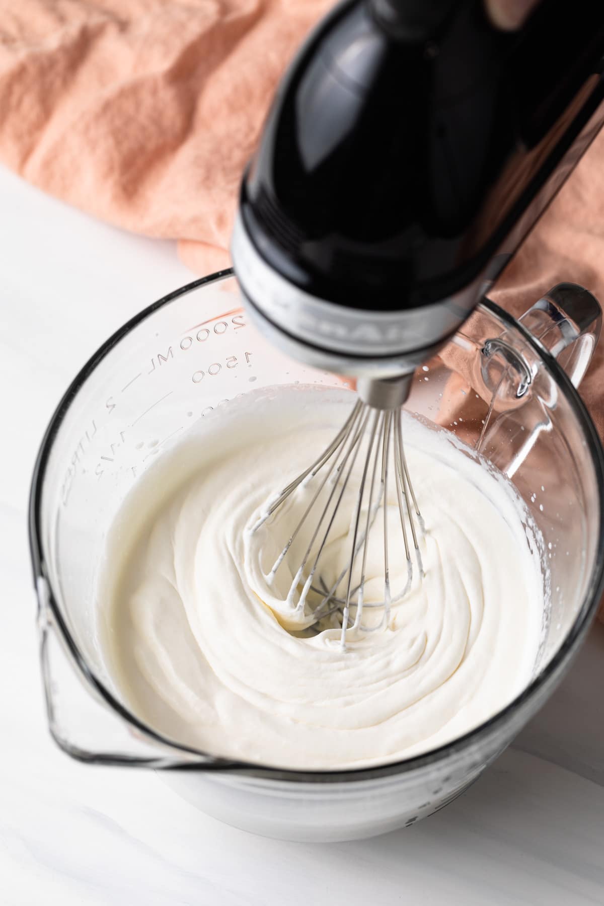 mixer whipping cream in a glass bowl