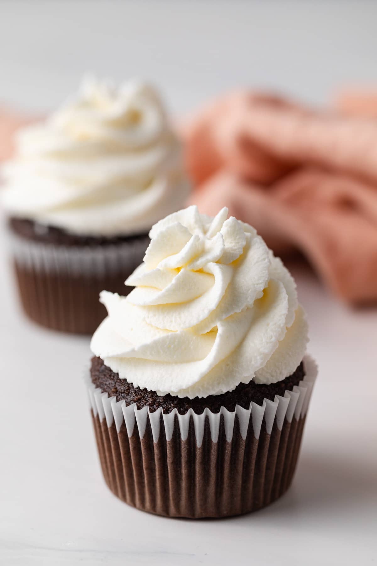 whipped cream swirled on top of chocolate cupcakes