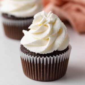 whipped cream swirled on top of chocolate cupcakes