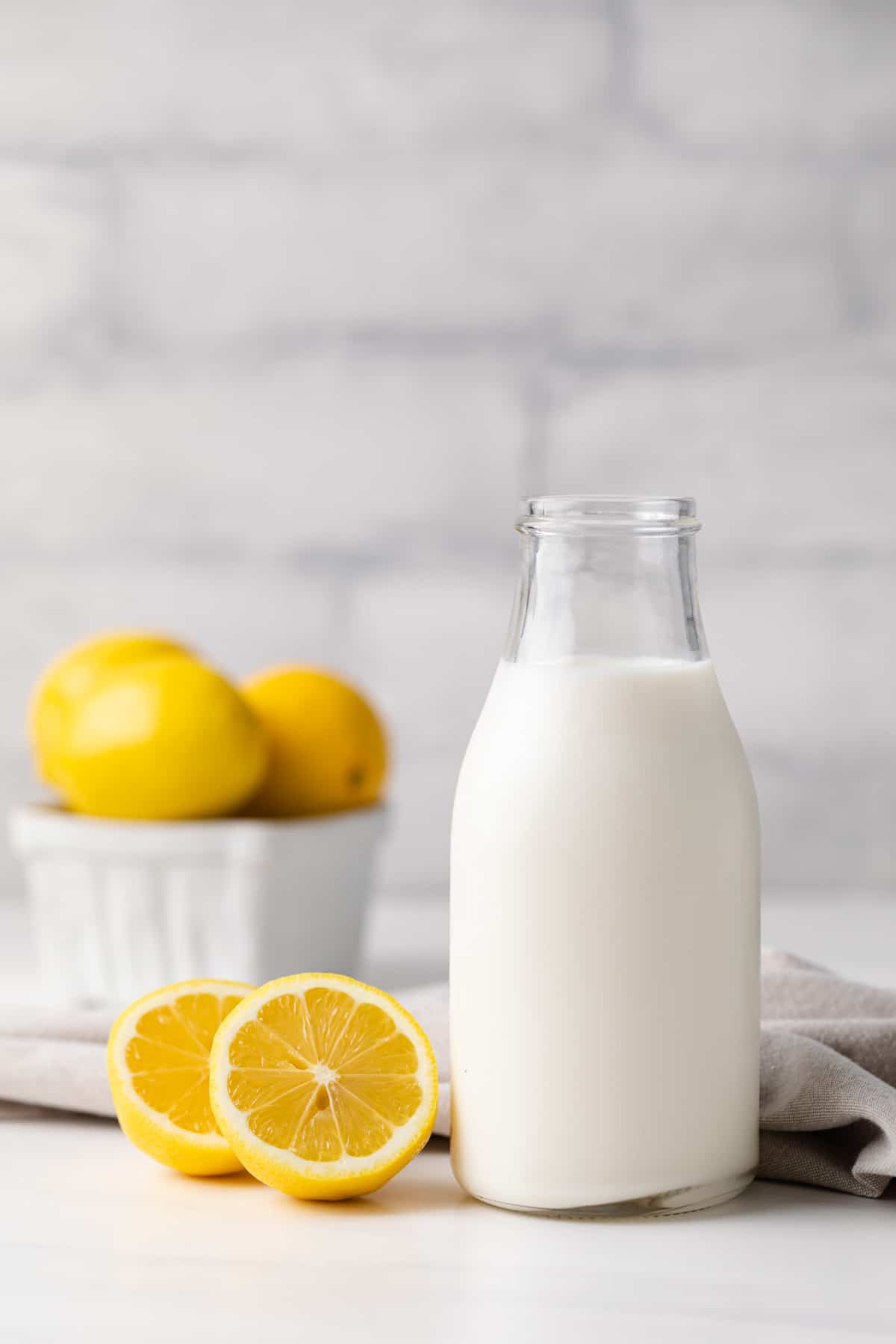 glass jar filled with homemade buttermilk along with a napkin and lemons in the background