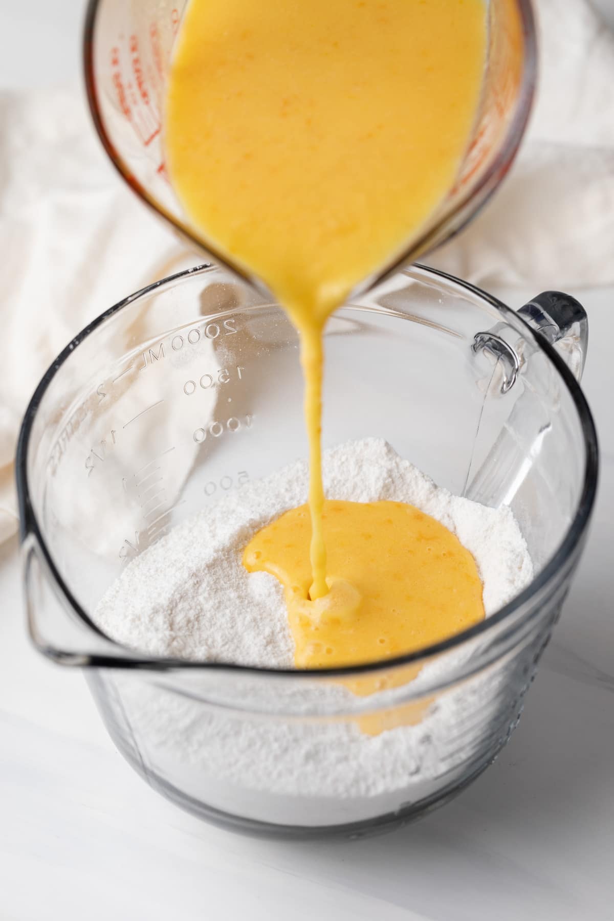 pouring wet ingredients into dry ingredients in glass bowl