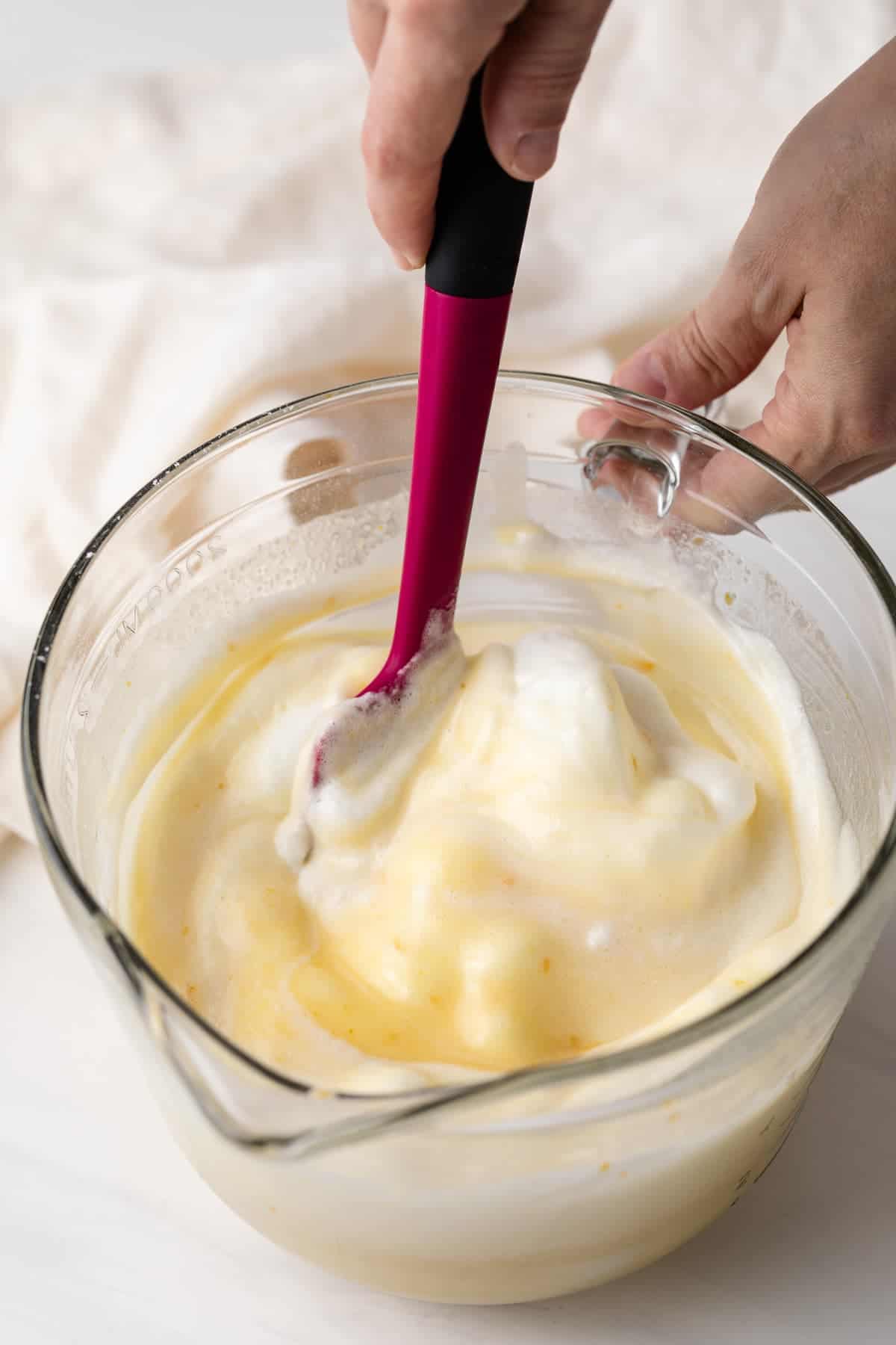 egg whites being folded into chiffon cake batter with pink spatula