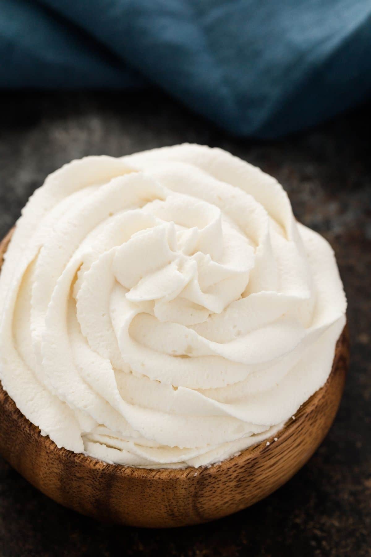 stabilized whipped cream swirled in a wooden bowl with blue napkin in the background