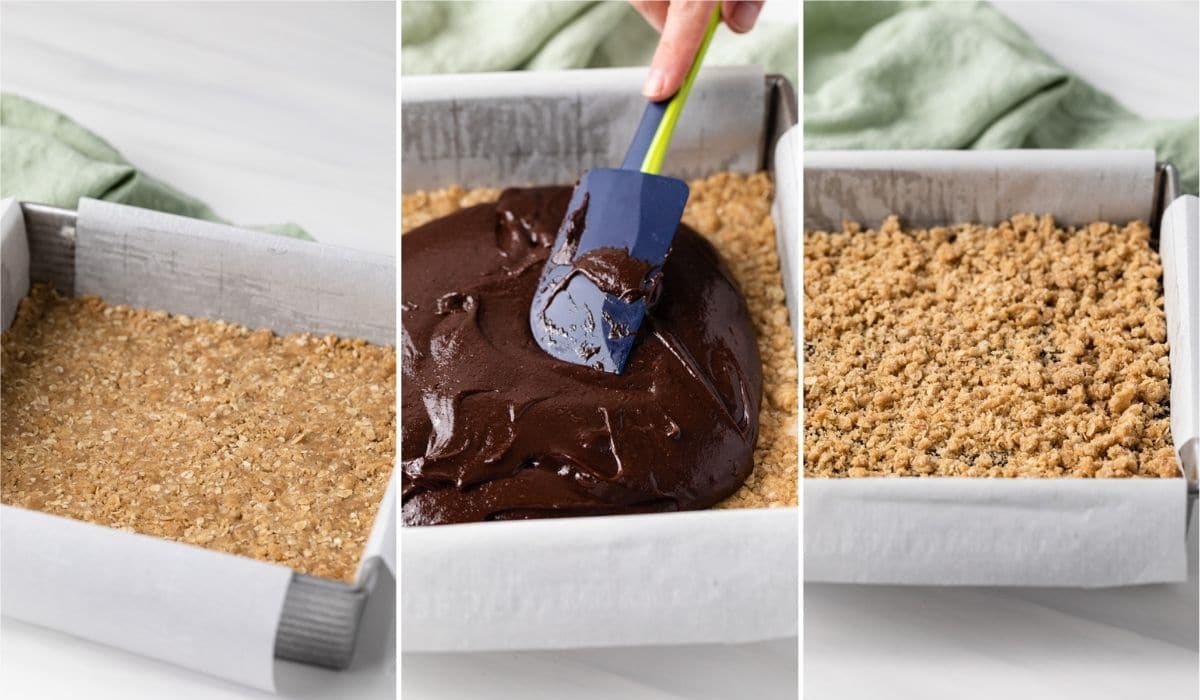 oatmeal base pressed into square pan lined with parchment paper, chocolate filling being spread over base with spatula, and more oatmeal crumbled over the top