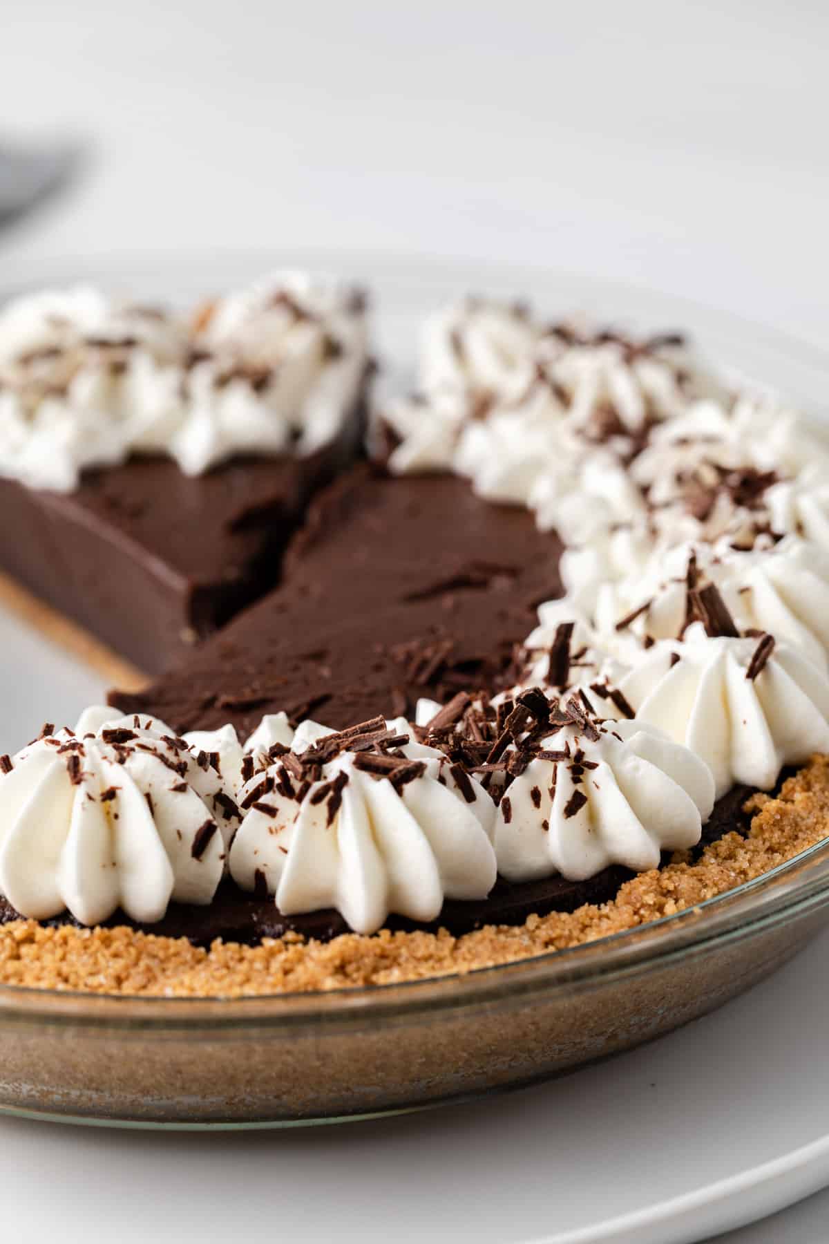 side view of chocolate pie topped with whipped cream and chocolate shavings in a glass pie plate