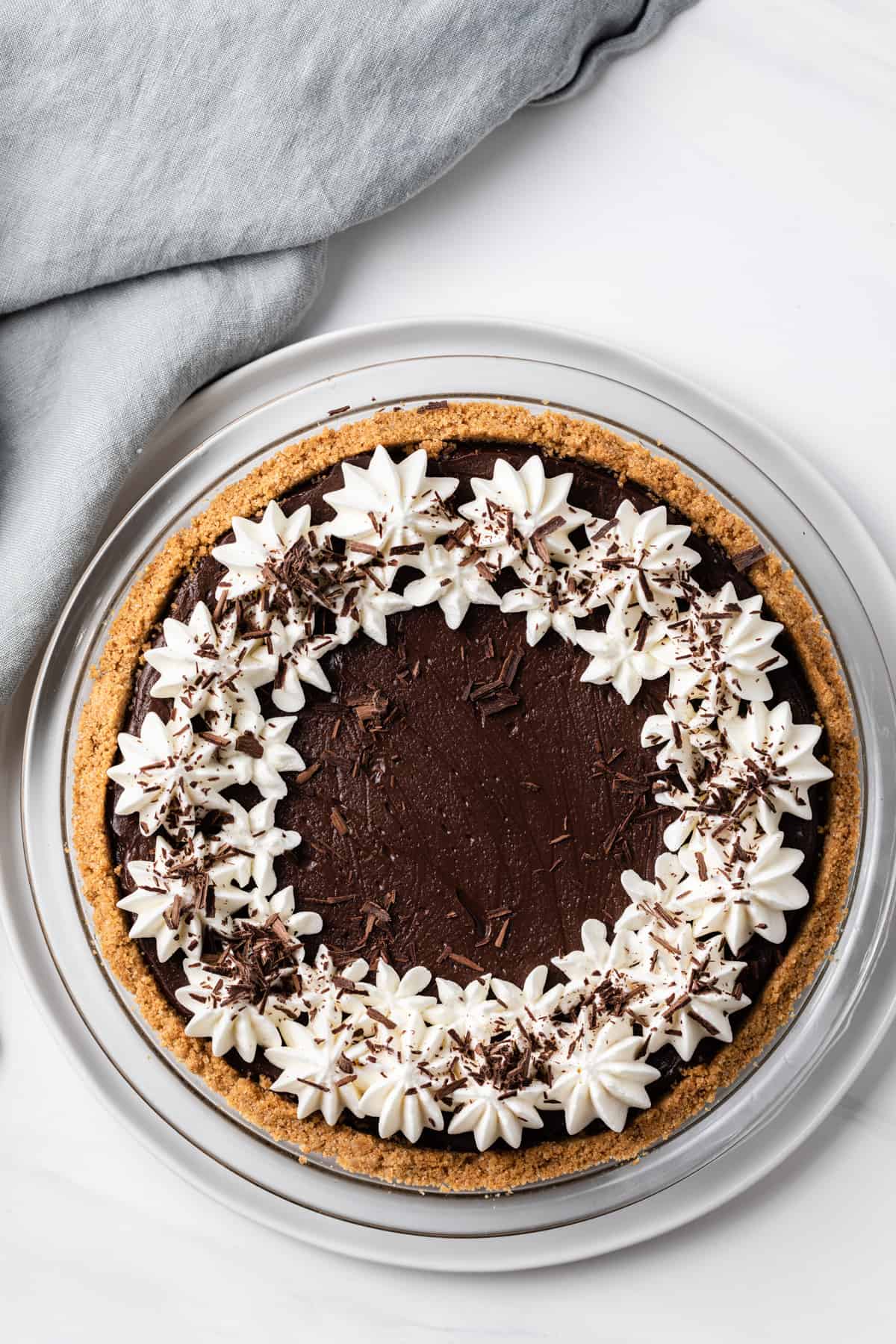 overhead view of chocolate pie topped with whipped cream and chocolate shavings in a glass pie plate
