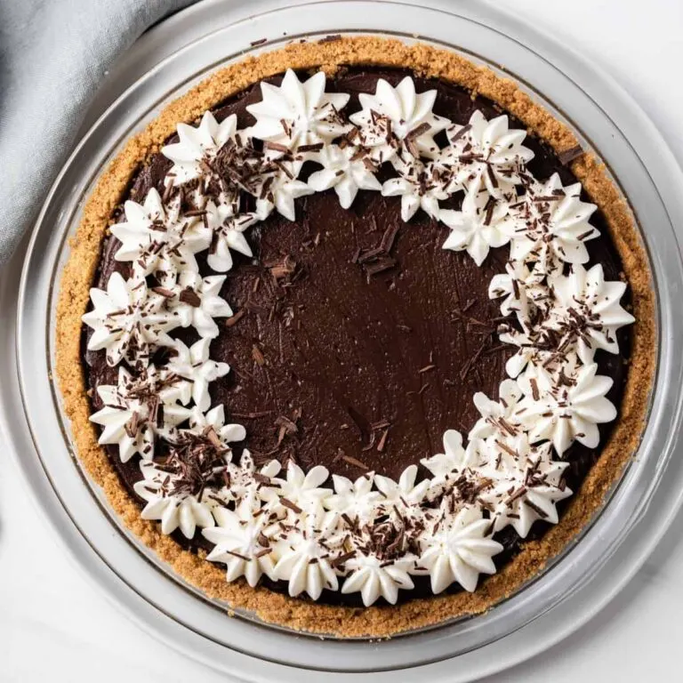 overhead view of chocolate pie topped with whipped cream and chocolate shavings in a glass pie plate
