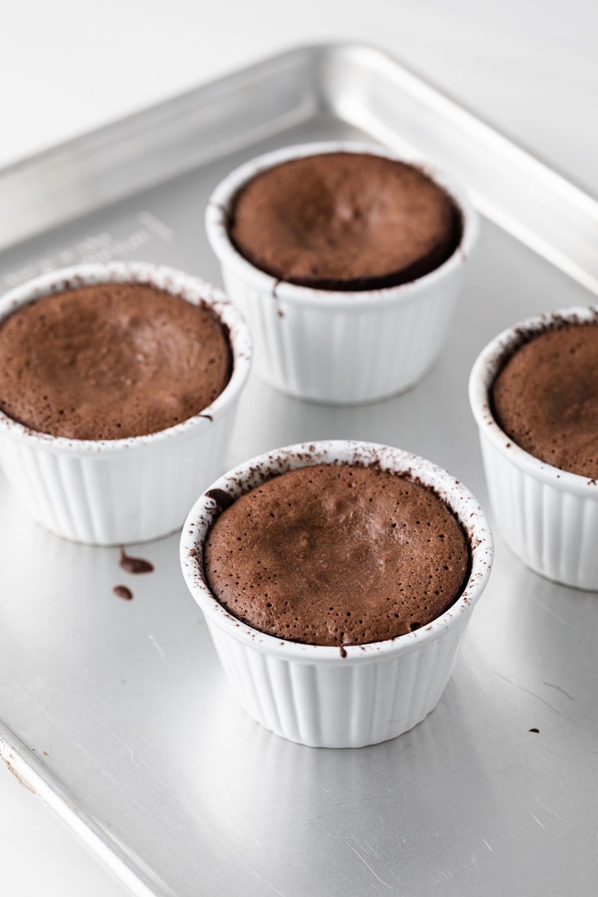 lava cakes baked in white ramekins on baking sheet