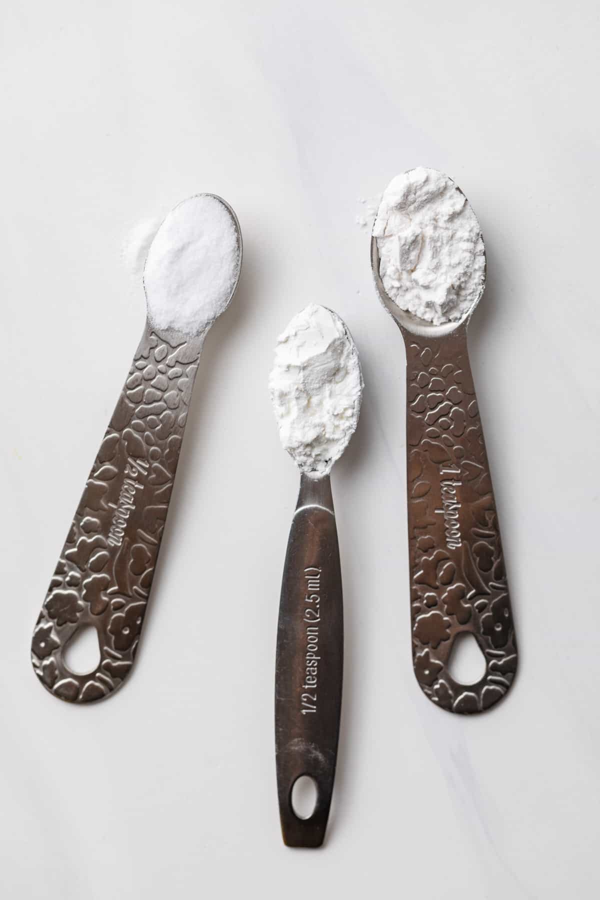measuring spoons filled with baking soda, cream of tartar, and cornstarch