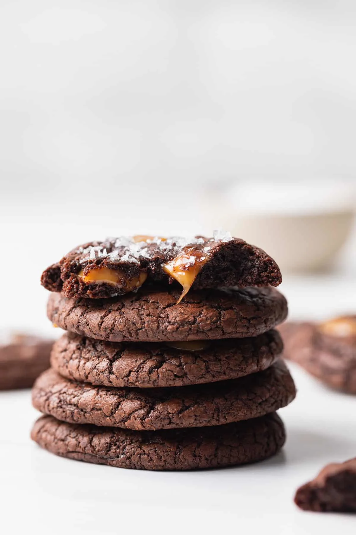 five salted caramel brownie cookies stacked with the top one broken in half so the gooey caramel is visible