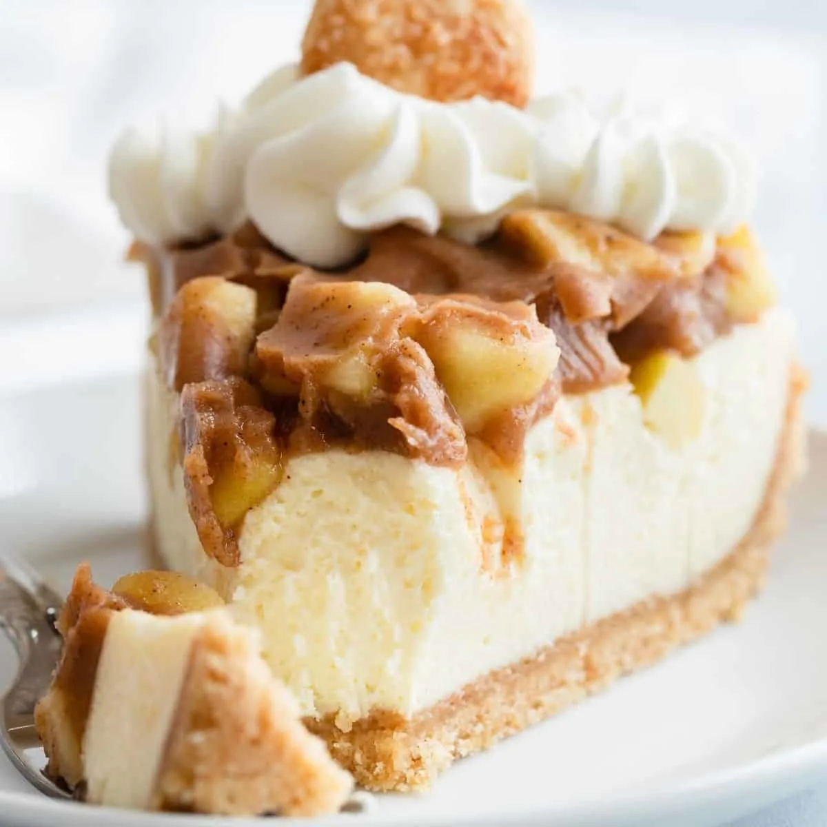 Close up of a slice of apple pie cheesecake with a bite taken out.