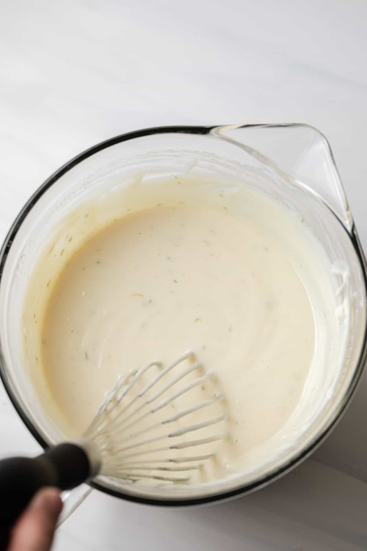 overhead of key lime pie filling in glass bowl with whisk