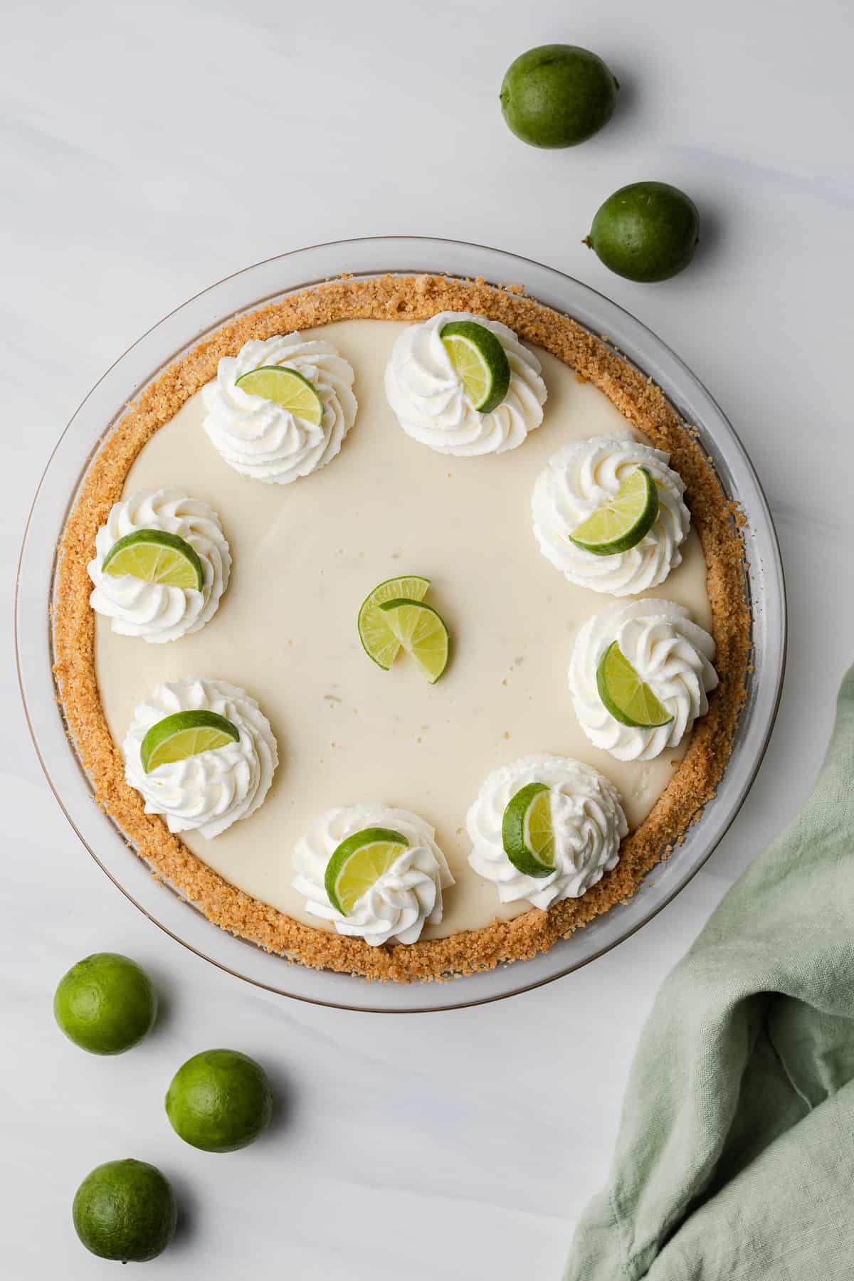 overhead of key lime pie topped with whipped cream swirls and lime slices