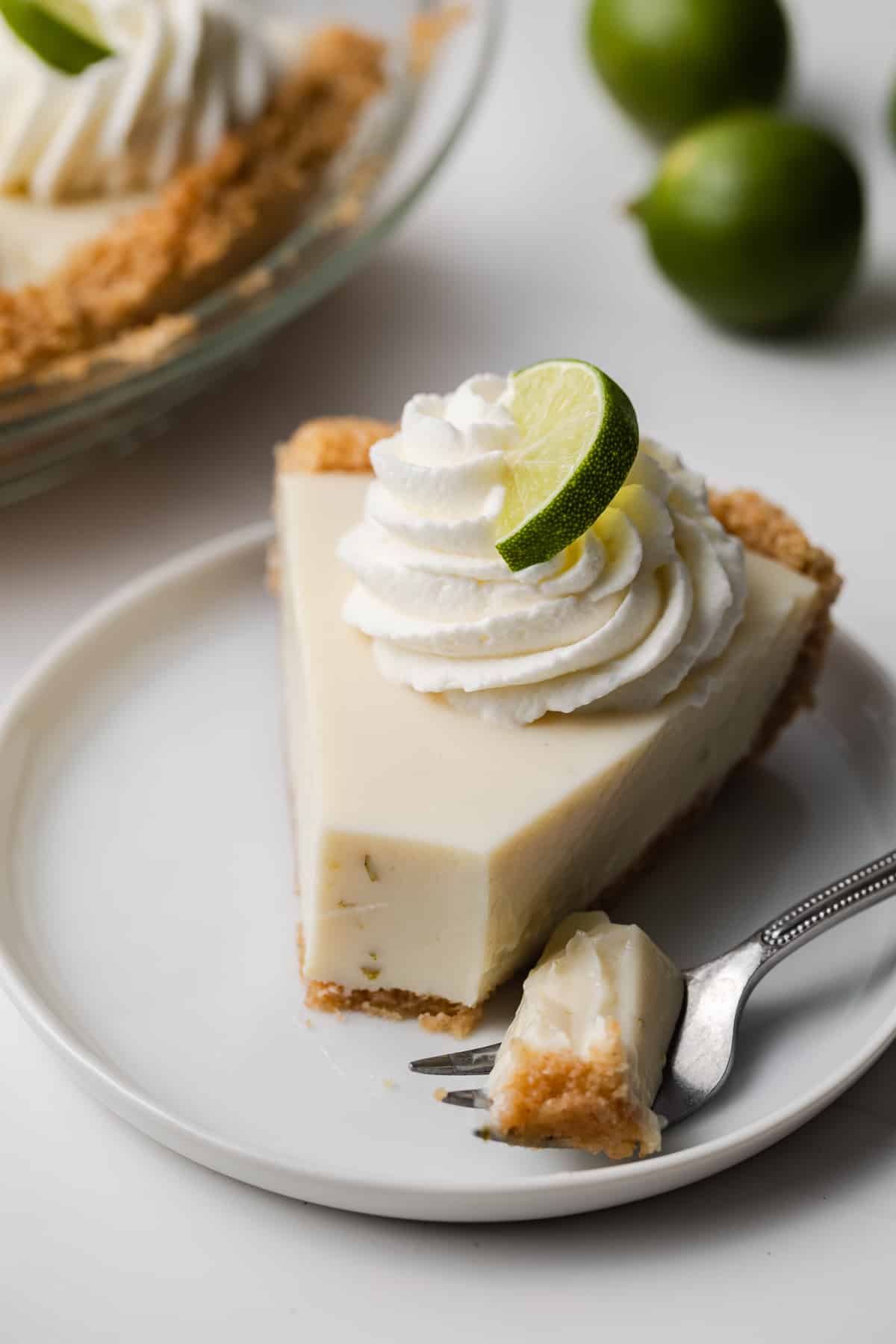 angled view of slice of key lime pie with fork taking a bite out