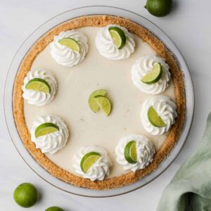 overhead of key lime pie topped with whipped cream swirls and lime slices