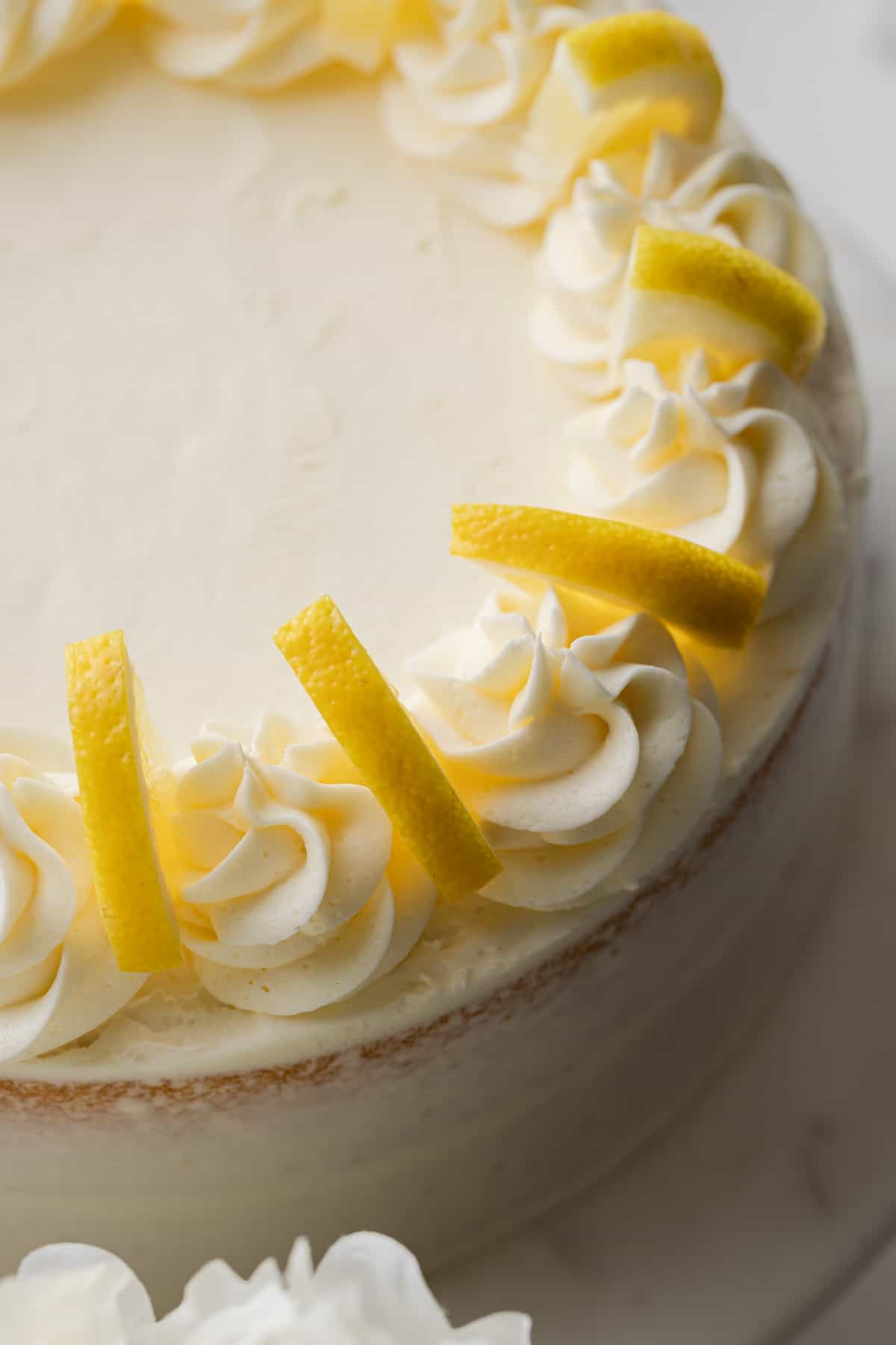 high angled view of lemon cake topped with swirls of lemon frosting and lemon slices