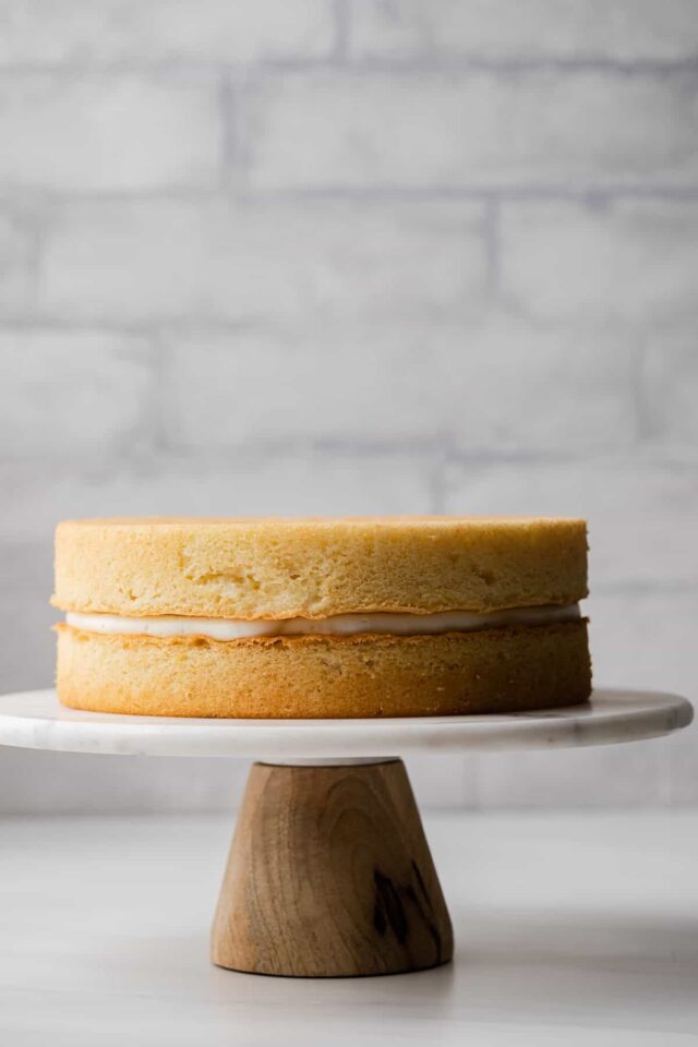 unfrosted lemon cake on a marble cake stand with wooden base
