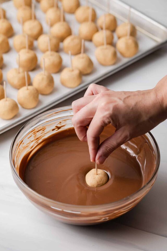 peanut butter ball being dipped into bowl of melted chocolate