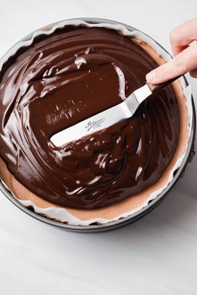 Ganache spread over mousse cake in pan.