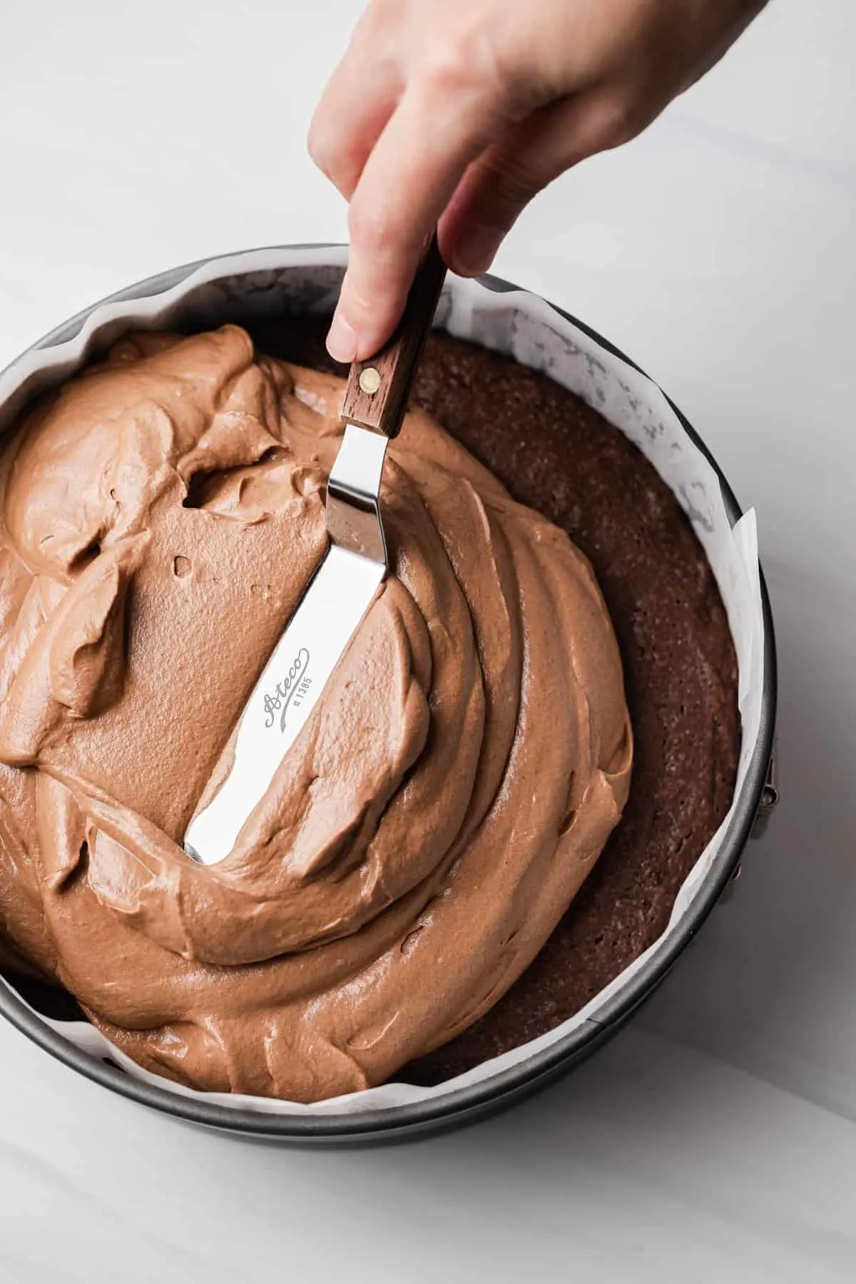 Chocolate mousse spread over brownie in round cake pan.