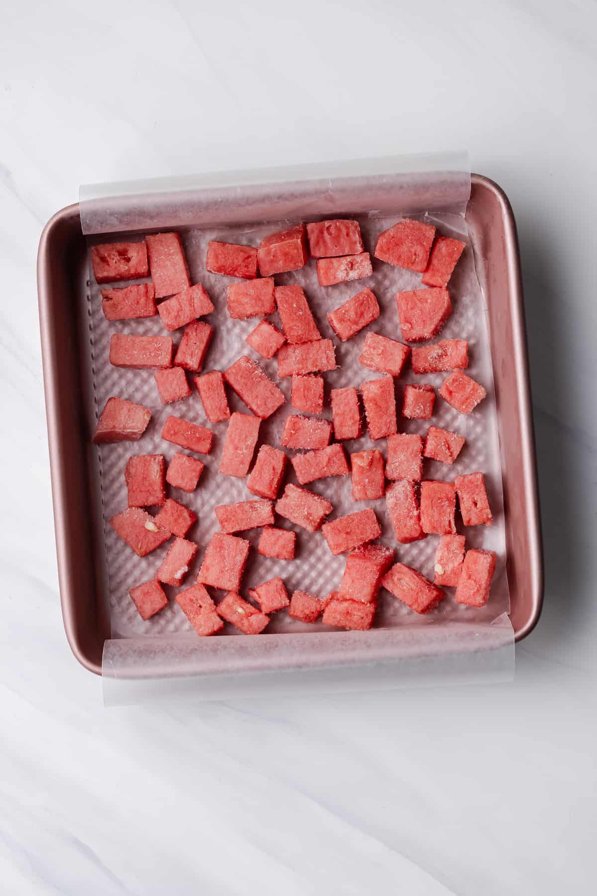 Frozen diced watermelon in square baking pan.