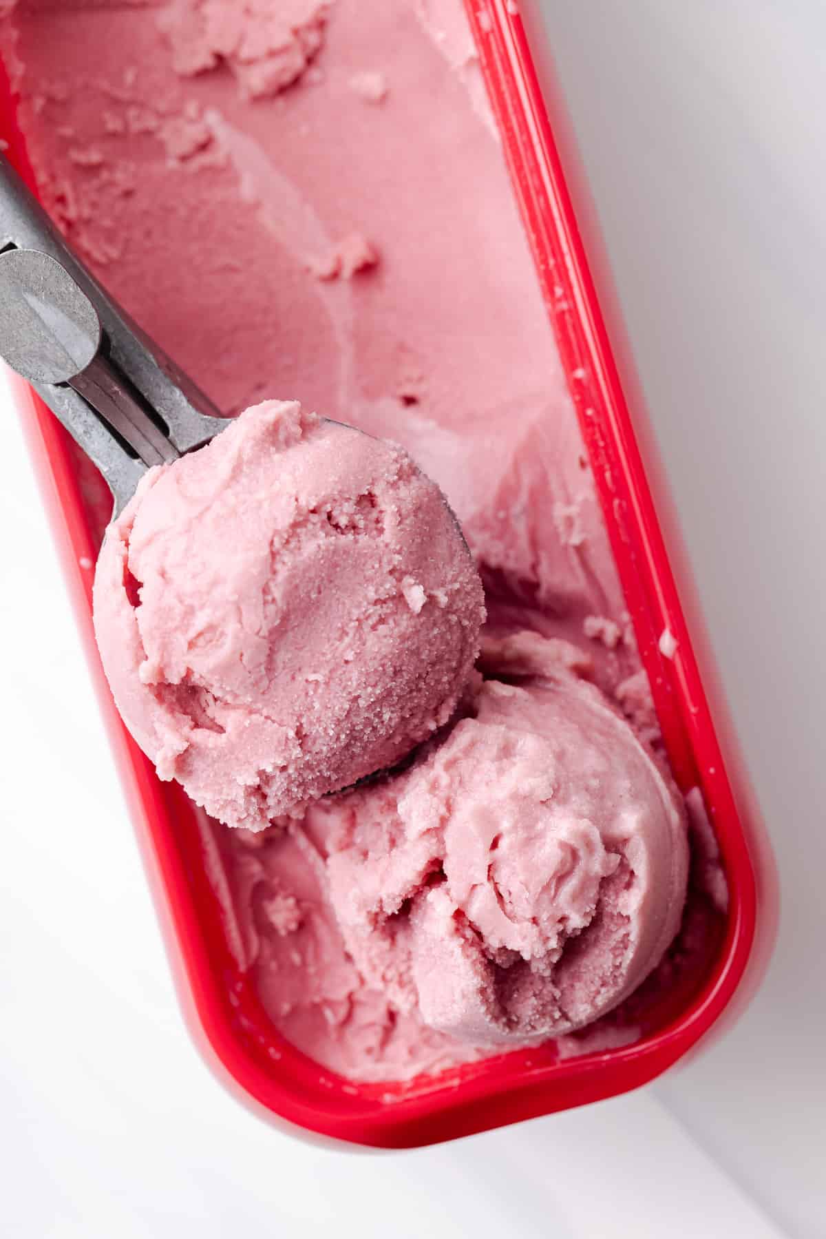 Over head of water melon sorbet in ice cream container.
