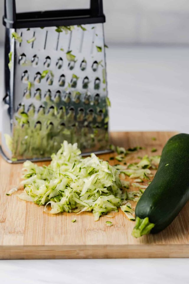 Grated zucchini on cutting board.