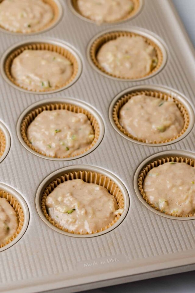 Muffin batter in muffin pan lined with paper cups.