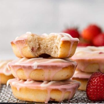 Baked strawberry donuts stacked on wire rack