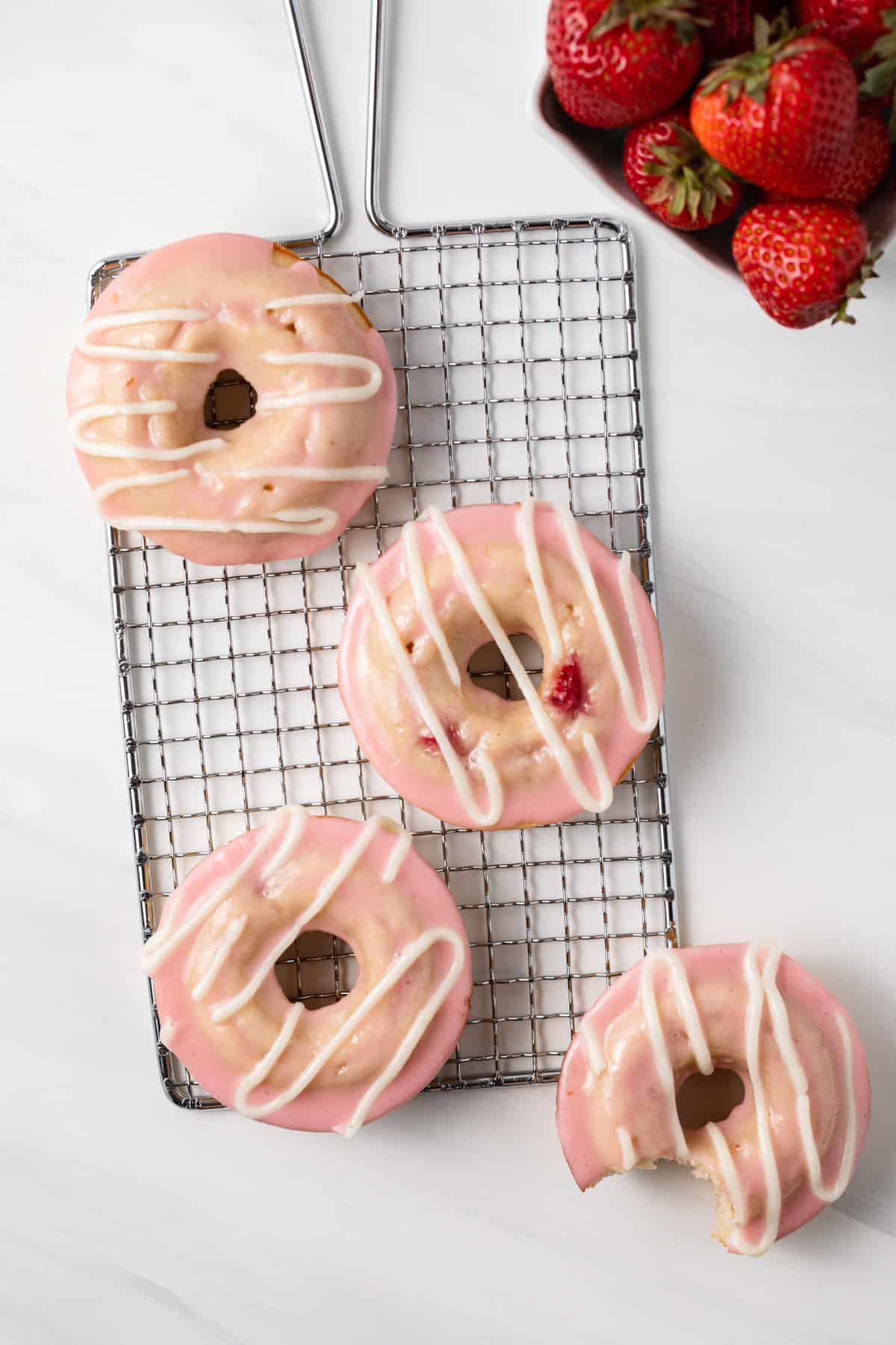 Glazed strawberry donuts on a wire rack