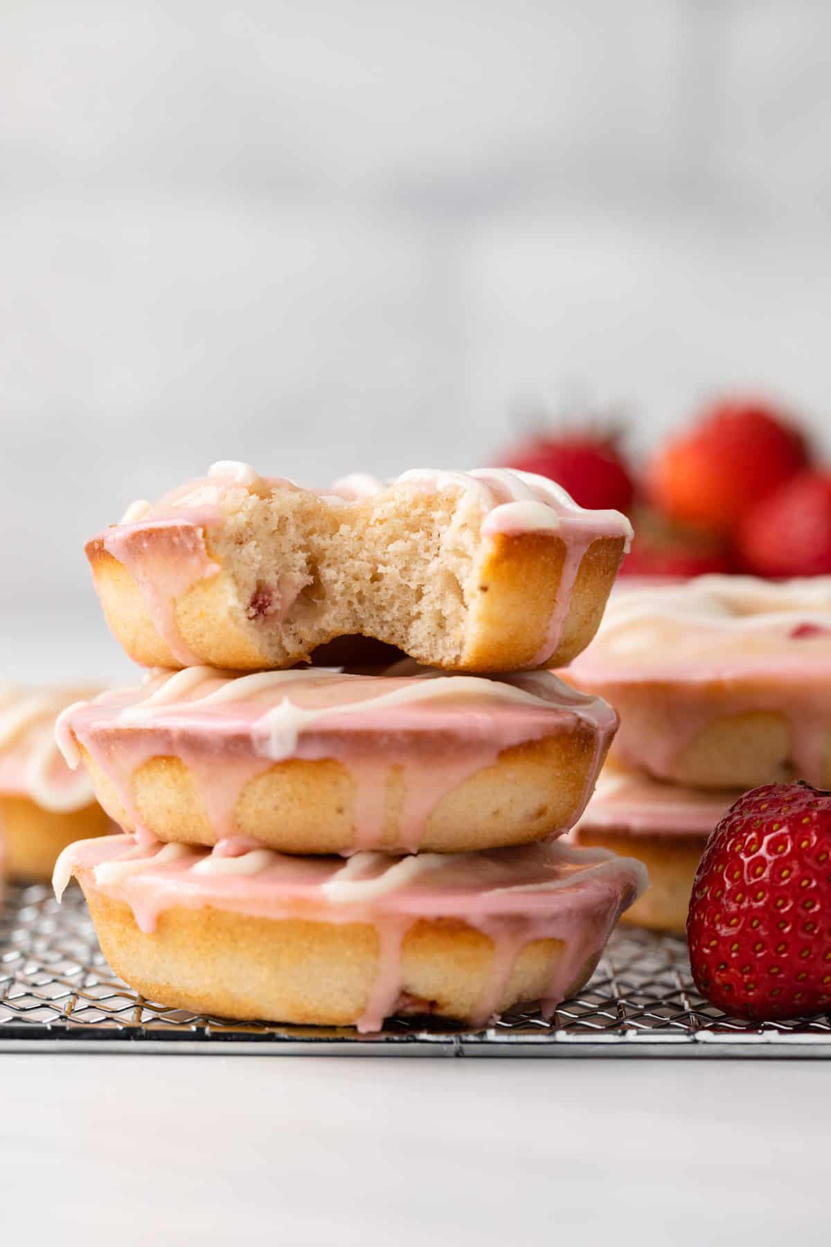 Baked strawberry donuts stacked on wire rack