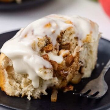 Freshly baked glazed apple cinnamon rolls on a plate with a fork