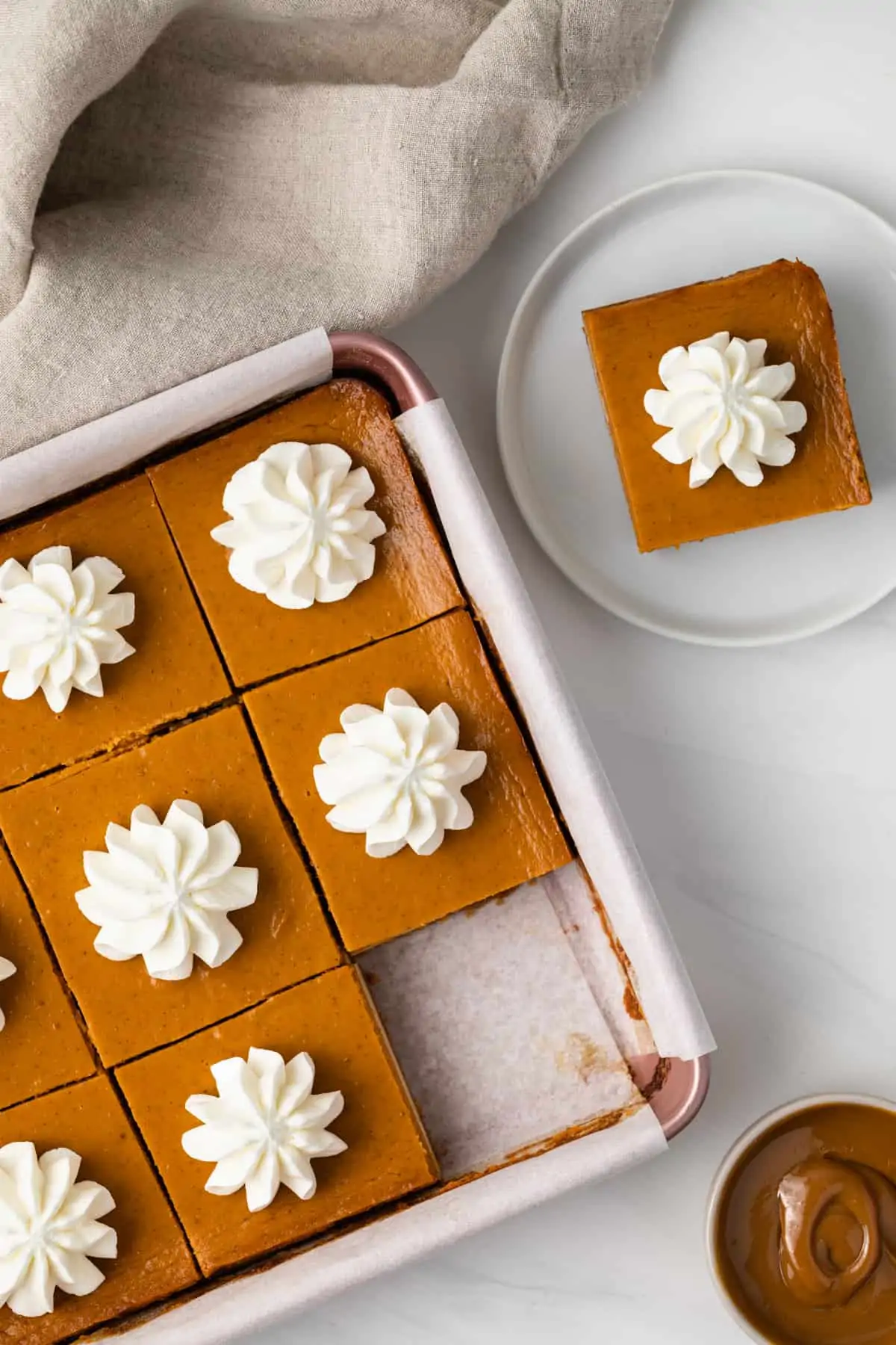 Overhead shot of Dulce de Leche Pumpkin Bars in pan with one removed and plated