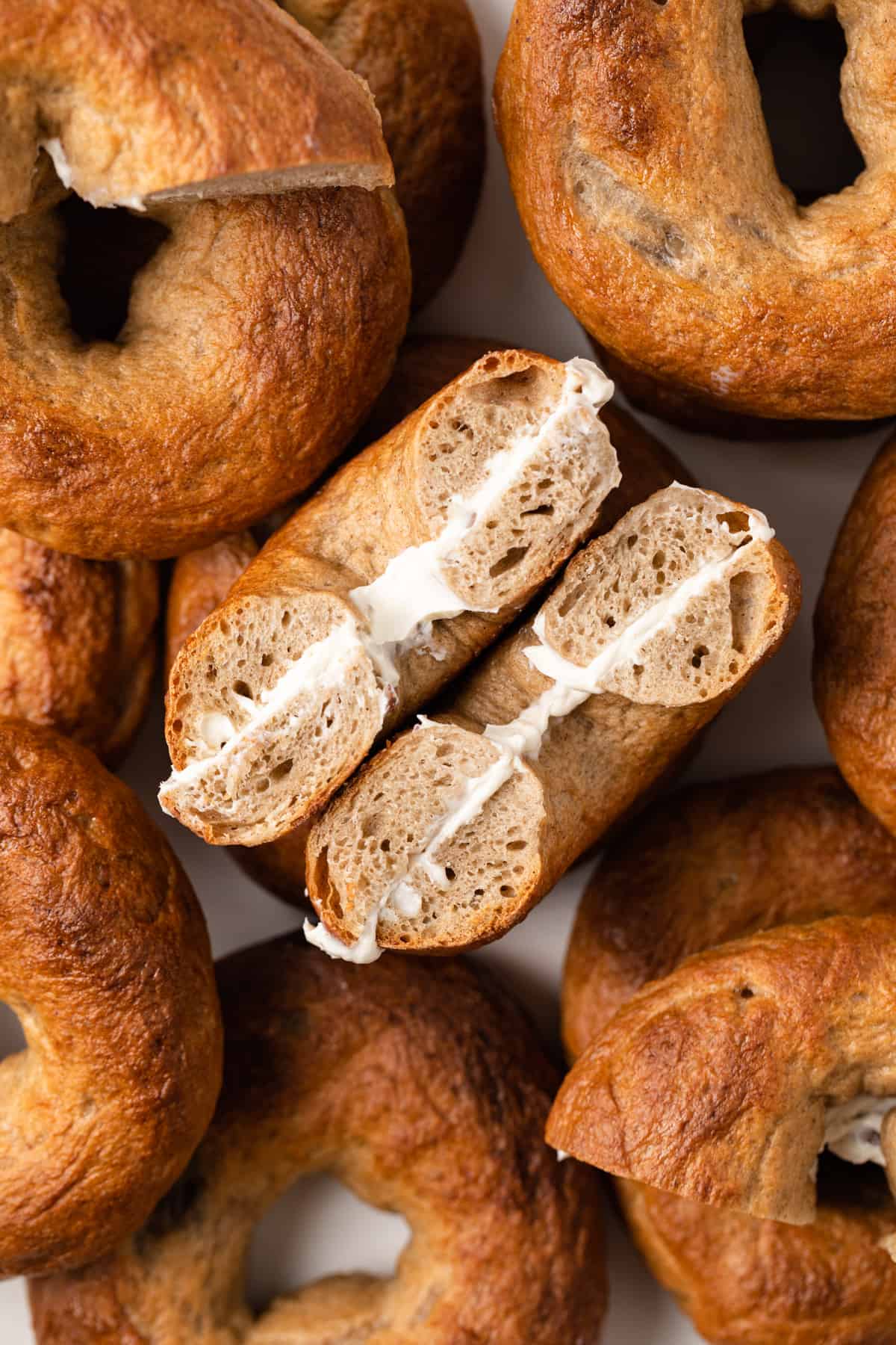 Closeup of Maple Cinnamon Bagels, with one in center cut in half and topped with cream cheese