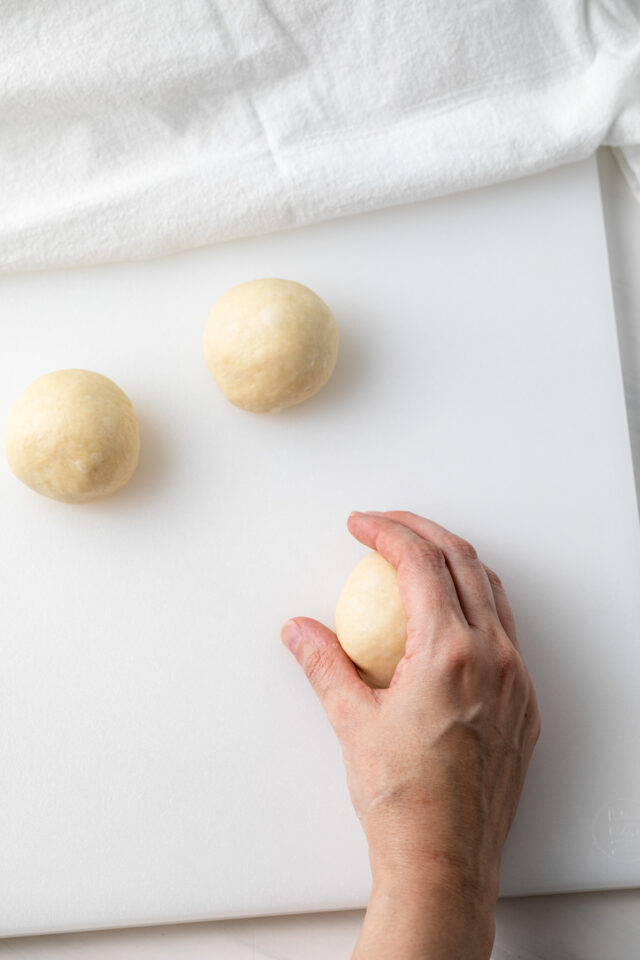 A hand shaping dinner roll dough