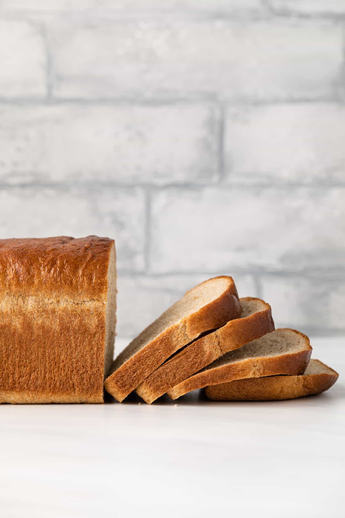 Side view of a loaf of whole wheat bread with half of the loaf sliced