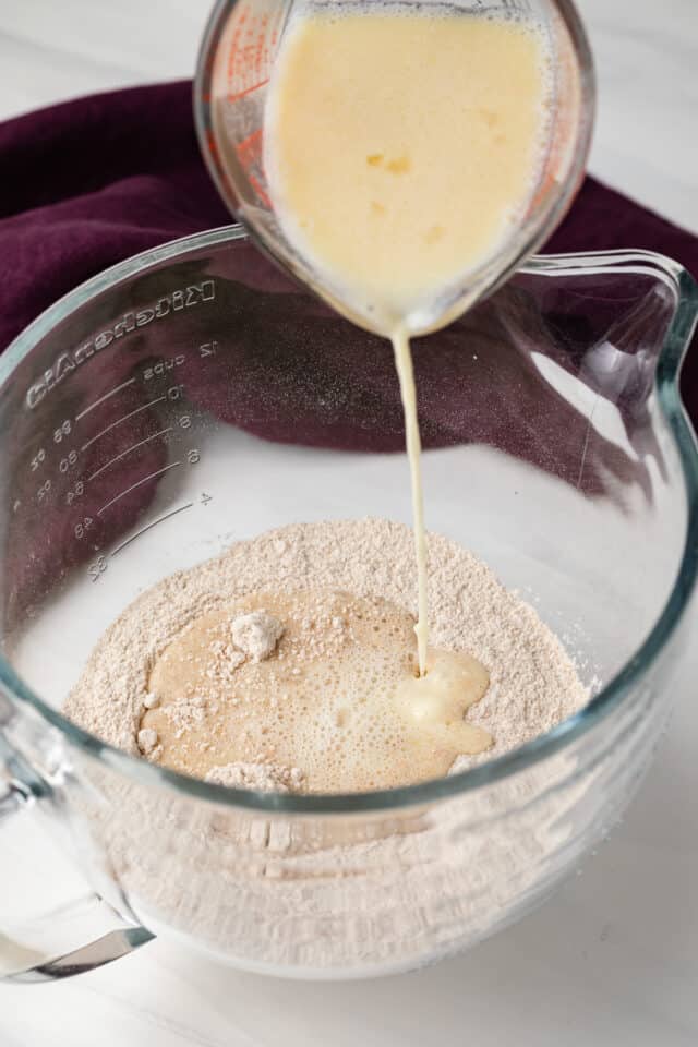 Liquid mixture being poured into bowl of flour