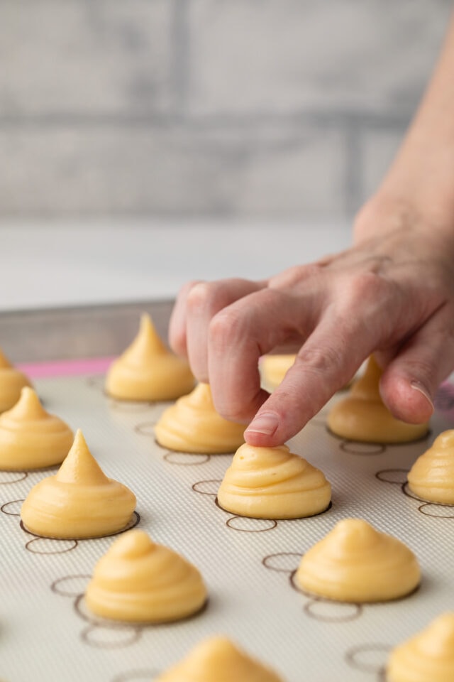 Finger pressing down tips of choux dough.