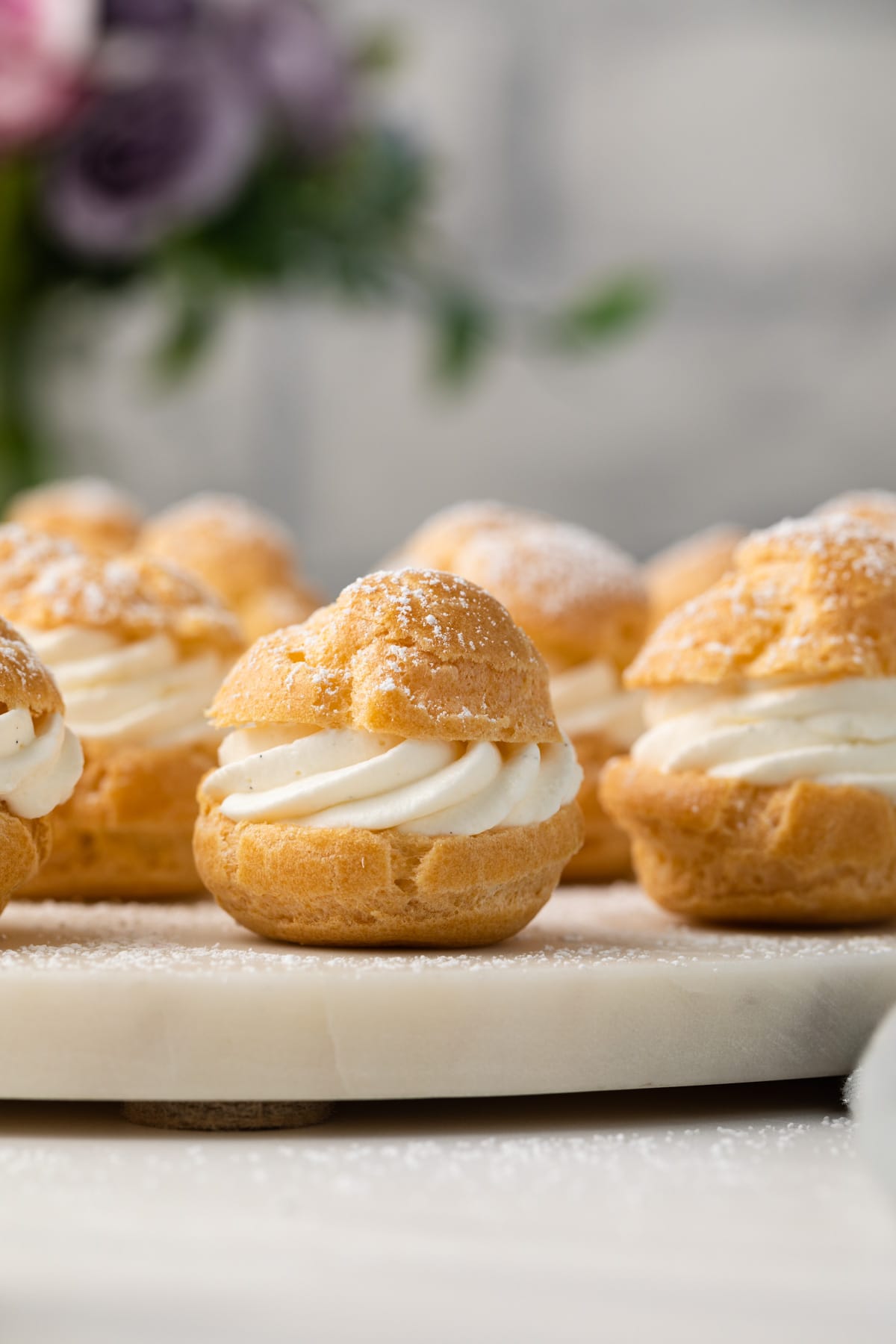 Homemade cream puffs on white stand.